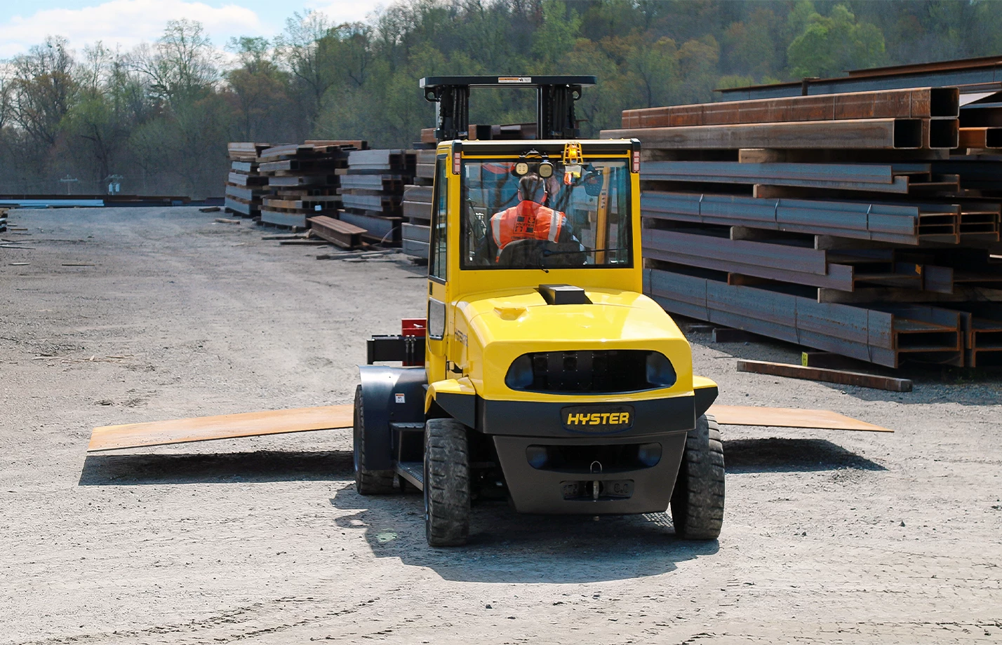 An operator moving materials through a lumberyard with a high-capacity Hyster forklift.