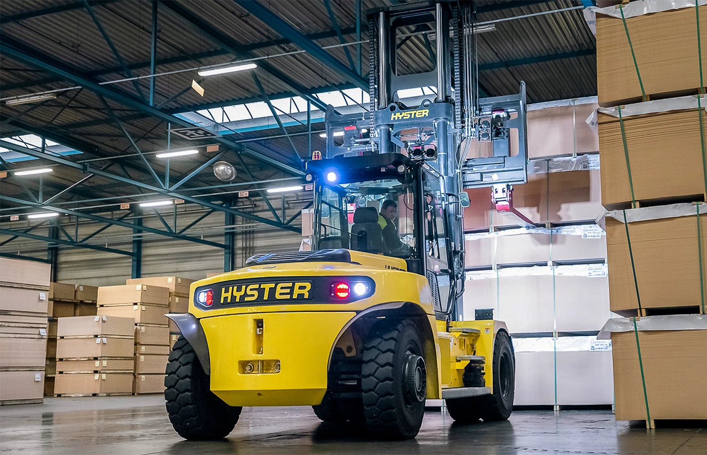 An operator using a high-capacity Hyster forklift inside an industrial warehouse.