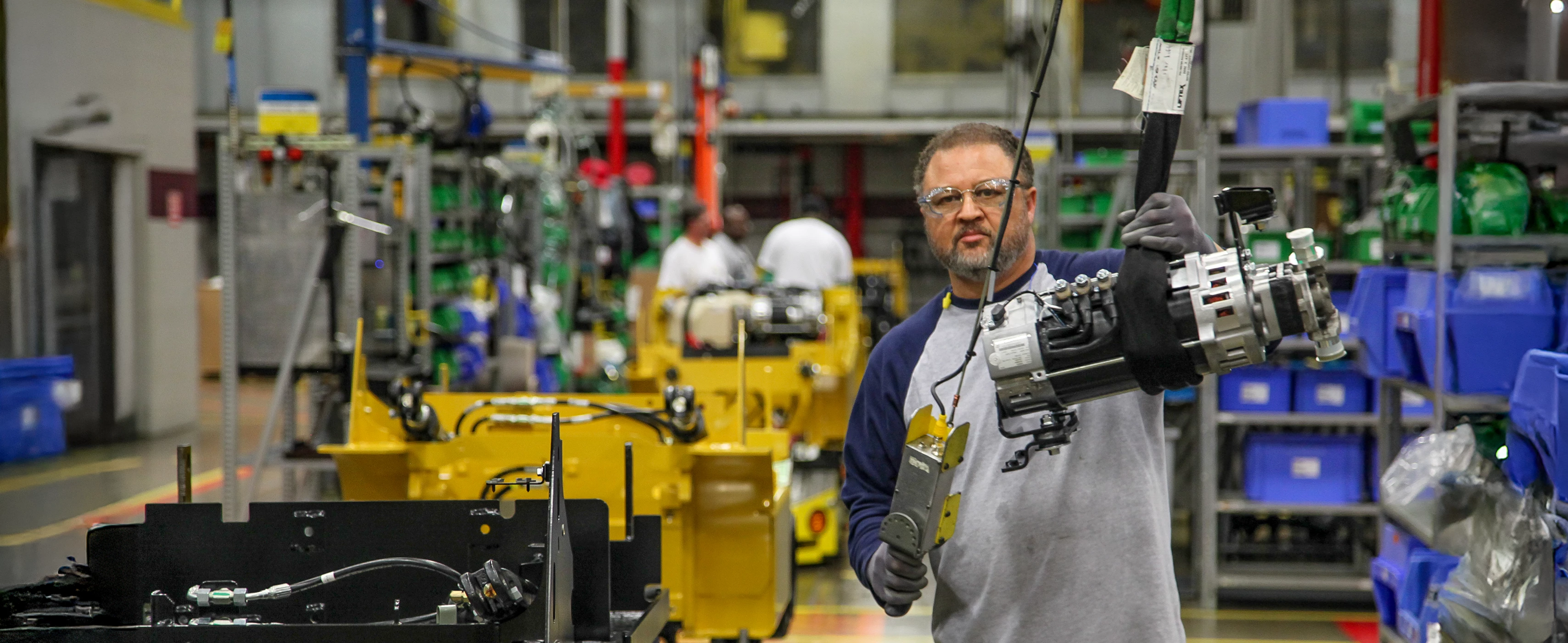 Man assembling forklifts in manufacturing plant.