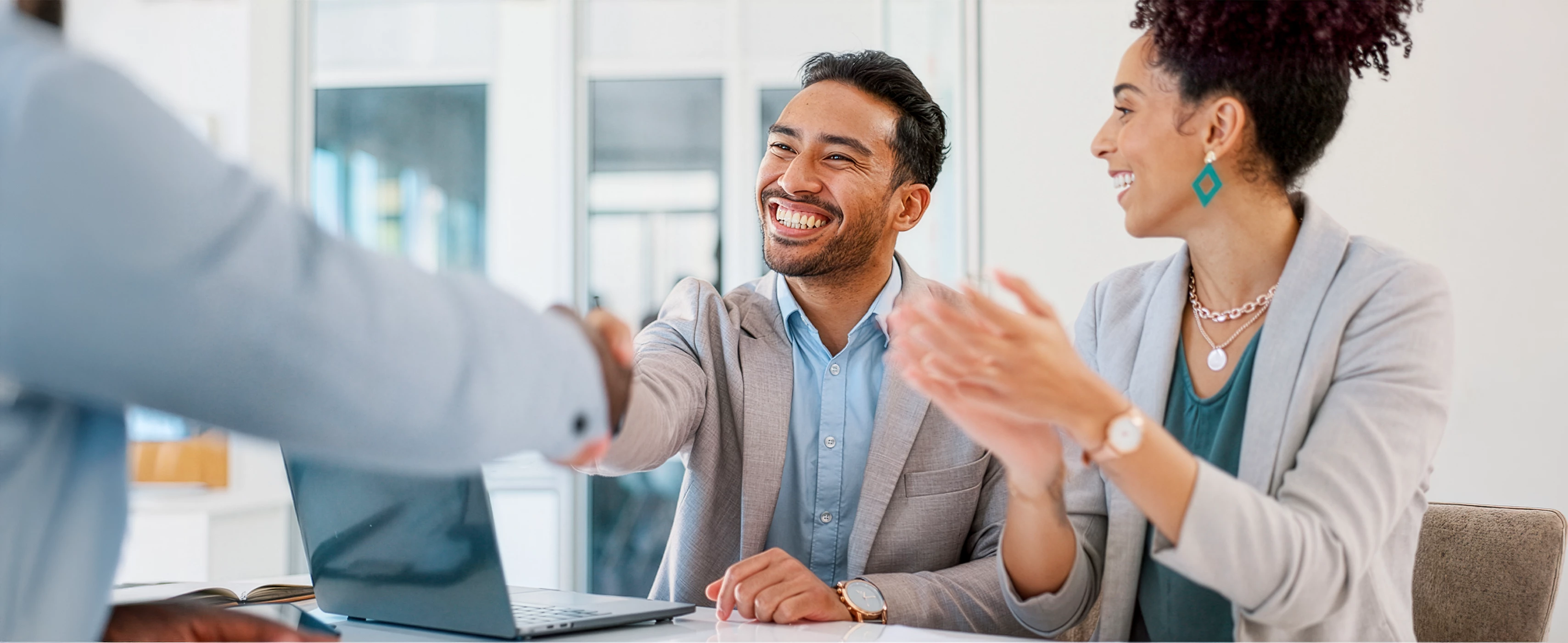 A man smiling and shaking someone’s hand.