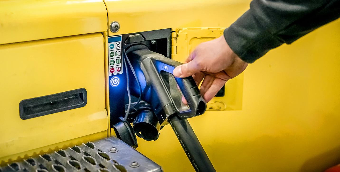 Person plugging in electric forklift to charge. 